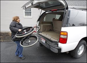 Cindy Parsons puts her son's wheelchair in their vehicle. He lost both of his legs and suffered other injuries in an explosion in Iraq.