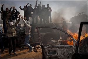 Libyan rebels celebrate as cars burn after Muammar Kaddafi's forces were pulled back from Benghazi, the last stronghold of the rebellion. Earlier, the city rocked with explosions as Kaddafi's troops entered the city.