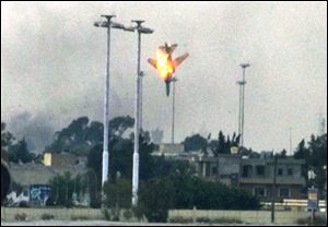 After possibly being shot down, an unidentified plane plummets to the ground over the outskirts of the rebel-held city of Benghazi, resulting in a fireball, right.