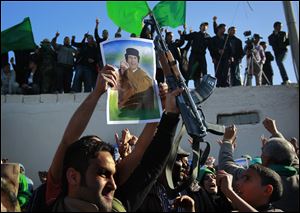 In  an organized trip by the Libyan authorities, people demonstrate their support for Libyan leader Moammar Kaddafi as they wait for the bodies of 26 people said to be killed during overnight air raids to arrive for burial in Tripoli Sunday.