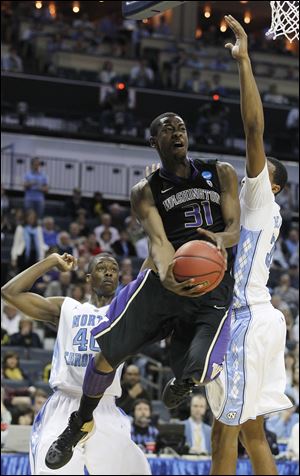 Washington guard Terrence Ross (31) heads to the basket as North Carolina forward John Henson, right, and North Carolina forward Harrison Barnes (40) defend.