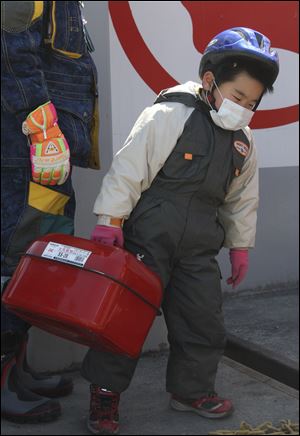 Six-year-old Satoshi Komatsu carries a gasoline container at a gas station in northern Japan’s Iwate prefecture.