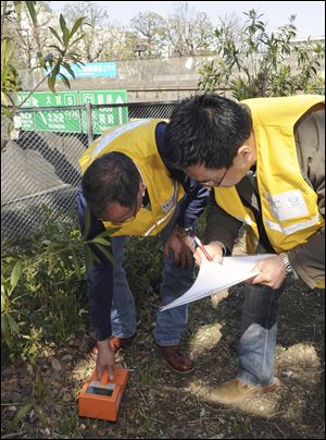 Officials from the United Nations International Atomic Energy Agency measure radiation exposure at a park in Tokyo. Minuscule amounts of radioactive iodine were found in tap water in Tokyo although experts said none of the tests showed health risks.