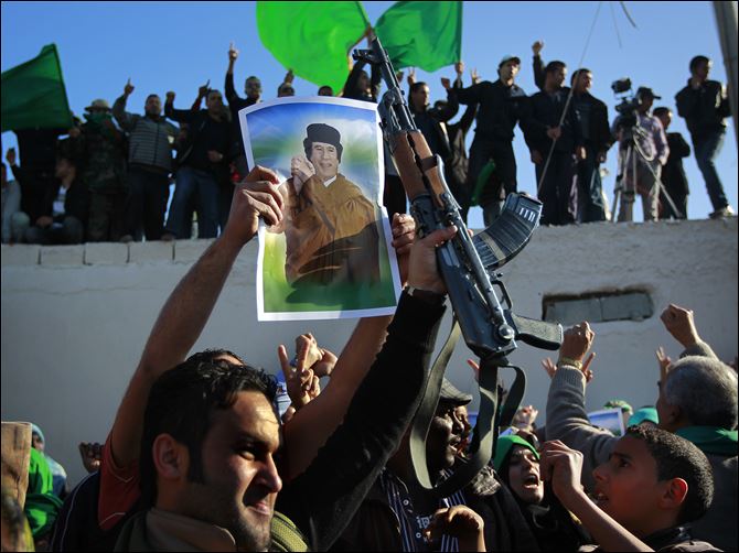 In  an organized trip by the Libyan authorities, people demonstrate their support for Libyan leader Moammar Kaddafi as they wait for the bodies of 26 people said to be killed during overnight air raids to arrive for burial in Tripoli Sunday.