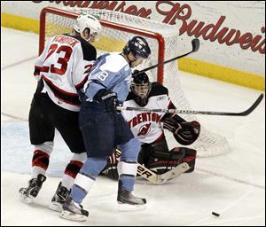 The Walleye's Randy Rowe battles for the puck with Trenton goalie Jeff Lerg and Taylor Vichorek at the Huntington Center Sunday.