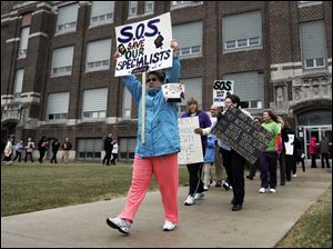 Marchers opposed to proposed cuts of art, music, and physical education teachers demonstrate outside the school system headquarters before the board meeting. The cuts are part of budget-balancing efforts.