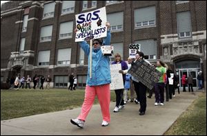 Marchers opposed to proposed cuts of art, music, and physical education teachers demonstrate outside the school system headquarters before the board meeting. The cuts are part of budget-balancing efforts.