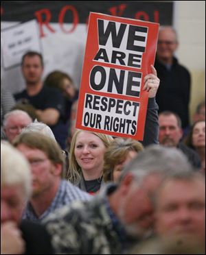 Lindsay Mylek-Douge holds a sign during a town hall meeting at Bedford Junior High School about road conditions. Hundreds of people attended the session.