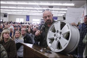 Edd McNulty shows a wheel rim, one of two he says were replaced at $225 a piece, after hitting potholes. He said people wanted to know why the state isn't doing anything.