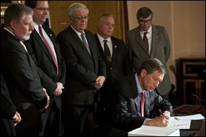 Gov. John Kasich inks Senate Bill 5 after the Statehouse had been locked for the night. Mr. Kasich said the bill restores the balance between the public and private sector.