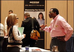 Kerry Murray, right, of DeVry University talks with a job seeker at a March job fair in Indianapolis.