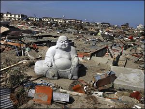 A statue of Hotei Buddha sits in the debris in the tsunami-destroyed town of Sendai, Miyagi Prefecture, northern Japan. Twenty-five thousand soldiers, 120 helicopters, and 65 ships will search for bodies through Sunday.