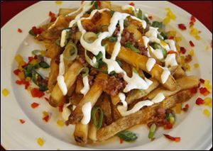 Bases-Loaded Fries are topped with cheese, bacon pieces, scallions, and sour cream.