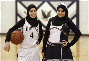 Yasmin Abdelkarim, 17, left, and Amal Mohamed, 15, right, are Muslim students at Maumee Valley Country Day School, dressed here in the attire they wear when they participate in their respective athletic activities. Yasmin plays basketball and Amal is a cheerleader.