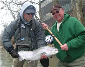 Steelhead guide Jim Chamberlin, left, hefts a 'steely' taken by Jeff Frischkorn during a recent outing on the Chagrin River near Willoughby in northeast Ohio