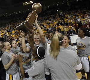 Jessica Williams, front, and Melissa Goodall hold up the trophy after the Rockets won the WNIT championship at Savage Arena. Toledo finishes the season with a record of 29-8. The win total is a program record.