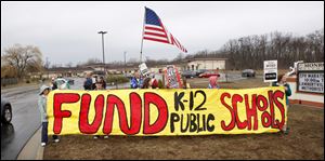 Members of the Bedford Education Association hold a banner outside Monroe Road Elementary School to protest Michigan Gov. Rick Synder’s proposed cuts to K-12 education.