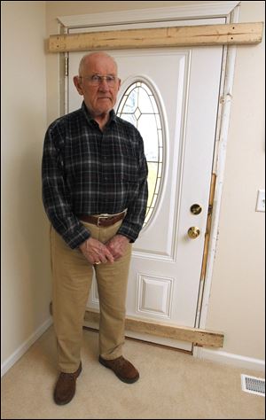 Erie Township resident Joseph Bodi, 78, stands by the front door  masked gunmen kicked in before they attacked him late Sunday night. It's now boarded up and a security system is scheduled to be installed.