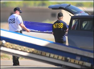 National Transportation Safety Board members carry a portion of the fuselage from the Southwest Airlines plane involved in the weekend incident to a waiting car as part of their investigation.