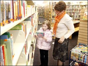 At the Waterville branch of the Toledo-Lucas County Public Library, Karen Wiggins helps Alivia Taylor, 7, of Monclova Township find materials. The library has far more to choose from today than at its start.