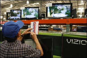 A shopper notes television prices at the Costco Wholesale store in Glendale, Calif.