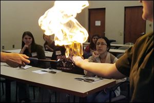 Edith Kippenhan, associate lecturer in the UT department of chemistry, lights a methane bubble for high school girls participating in the university's Women in Science Day. 