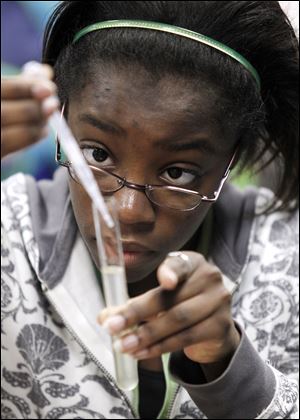 Jasmine Williams, 16, a junior at Bowsher High School, adds alcohol to a test tube containing a cell from her cheek. 