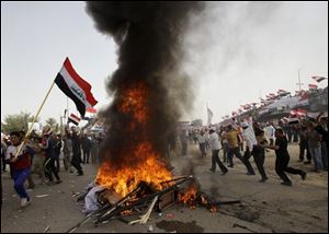 Followers of radical Shiite cleric Muqtada al-Sadr wave Iraqi flags as they burn an effigy of former U.S. President George W. Bush and U.S. flags during a rally marking the eighth anniversary of the fall of the Iraqi capital to American troops in Baghdad.