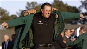 Former Master's champion Angel Cabrera, left, of Argentina helps Phil Mickelson put on his Masters jacket after his win at the 2010 Masters golf tournament in Augusta, Ga.