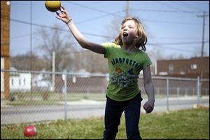 Hailie Draper, 10, takes aim in an attempt to hit her brother with a ball during a game of dodge ball in the front yard of their home on Western Avenue. The high temperature Sunday topped out at 83 degrees and tied the record.