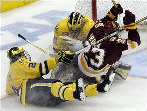 Minnesota Duluth right wing J.T. Brown (23) collides with Michigan goalie Shawn Hunwick, center, after a holding penalty by Michigan defenseman Jon Merrill, left, during the third period.