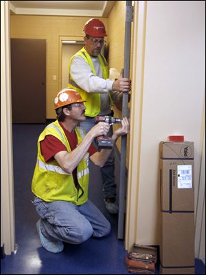 Construction workers Ron Vidra, left, and Paul Langdon install a door  inside the new Lake Township administration building. It replaces one destroyed by a tornado that struck the township June 5, 2010, and killed seven people.