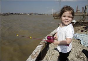 Alexis Futrell, 2, of Toledo gives a try to fishing in the Maumee Sunday and enjoys the return of T-shirt weather.