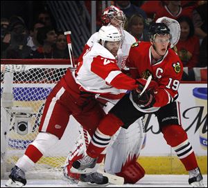 Detroit Red Wings' Brad Stuart, left, tries to keep Chicago Blackhawks' Jonathan Toews from planting in front of Red Wings goalie Jimmy Howard, center, during the first period Sunday.