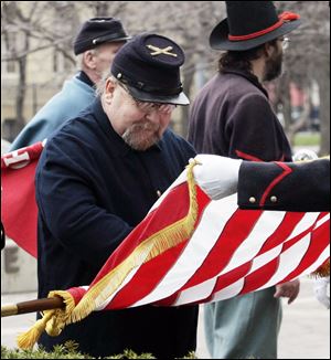 Randy Schimming of Battery H, 1st Ohio Light Artillery, a re-enactors group, folds the U.S. flag after the ceremony at Civic Center Mall. More than 1,000 area men joined the northwest Ohio regiment that was sworn in in Cleveland to fight in the Civil War.