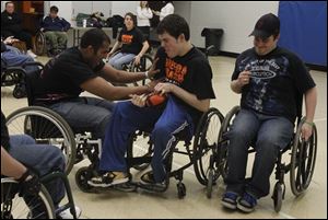 Amit Goyao, left, of Toledo, tries to 'tackle' Nick Hyndman, right, a member of the Toledo Crash wheelchair football team from Perrysburg, during a scrimmage with the University of Toledo Rec Therapy Club.