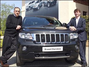 Fiat and Chrysler CEO Sergio Marchionne, left, poses with the new Grand Cherokee Jeep and Mike Manley, Jeep brand CEO, during a presentation Monday in Balocco, near Turin, Northern Italy.