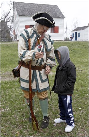 Jim Watko, dressed as a militiaman, shows his sword to Travis Burt, 7, Toledo.