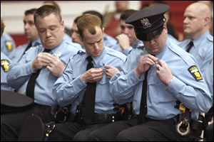 Anthony Foley, left, Melvin Haney, Jr., center, and Brian Heath pin on their badges after being sworn in as members of the Toledo Police Department Tuesday night.