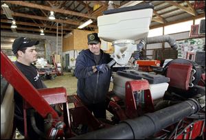 Bill Myers, right, and his son John Myers work on their corn planter in Oregon, Ohio. Mr. Myers says he'll increas corn production by 15 percent to 20 percent because he cut back last year.