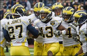 Michigan safety Carvin Johnson (13) celebrates his interception with Mike Jones (27), Cameron Gordon (4), and Marrell Evans, far right. Johnson also had seven tackles. 