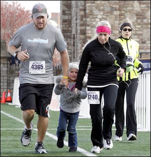 Jared Okoneski, left, and his wife Kelly Okoneski, right, from Perrysburg, run across the finish line in the half marathon with their daughter Brooklyn, 4, who joined them for the final 100 yards.