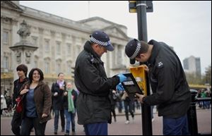 Metropolitan police officers carry out security checks on traffic lights, along the Mall in central London, ahead of the Royal wedding. 