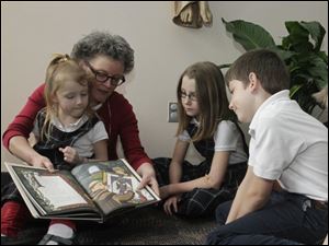 Children’s book author Cindy Millen Roberts reads her book ‘The Ink Garden of Brother Theophane’ to Christ the King school students, from left to right, Clare Dillon, 6, fourth grader Hope Th ayer, Joe Dillon, 10, and Steve Dillon, 8, on Friday.
