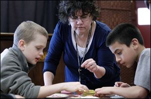 Sharon Anderson, center, helps Jeffrey Baer, left, 11, and Emanuel Dominguez, 11, right, make Easter egg decorations.