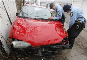 New Officer Jamie Brown, right, inspects a damaged vehicle in an alley with Officer Amy Herrick, his field training officer.