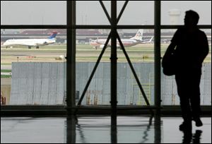 A traveler is seen in Terminal C at Dallas Fort Worth International Airport as aircraft taxi along a runway in Grapevine, Texas.