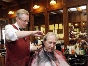 The Rev. Bob Wilhelm gets his hair cut by barber Bert Mills at the barbershop inside the Toledo Club. Mr. Mills operated a shop in the Spitzer Building downtown for 21 years, moving out last week. 