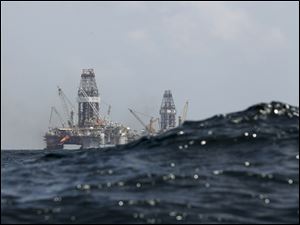 A swell partially obscures the Development Driller II, left, and Development Driller III, which drilled relief wells last summer at BP's Deepwater Horizon oil spill site in the Gulf of Mexico off the Louisiana coast. 