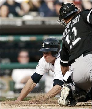 Detroit's Brandon Inge, left, dives past Chicago catcher A.J. Pierzynski to score from third base on a single by Magglio Ordonez in the fifth inning of a baseball game on Saturday.